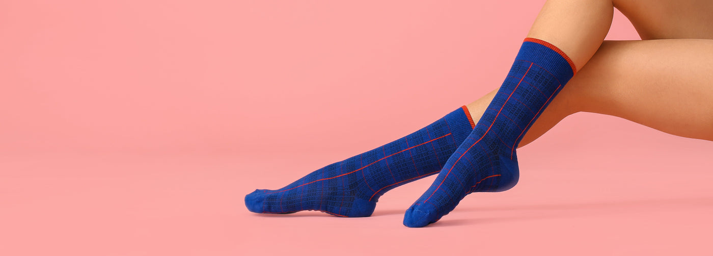 Ladis feet with blue socks on a pink background