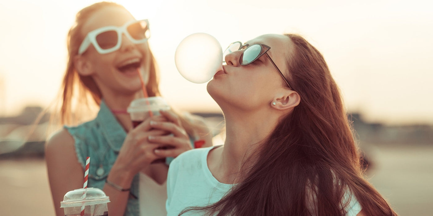 Teen girls with accessories laughing and blowing a gum bubble